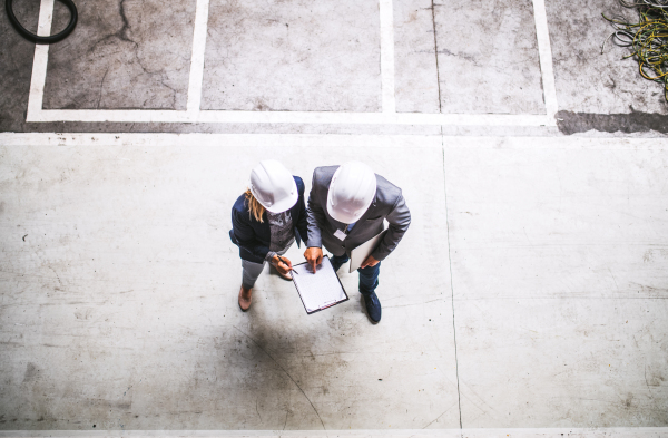 A top view of an industrial man and woman engineer with clipboard in a factory. Copy space.