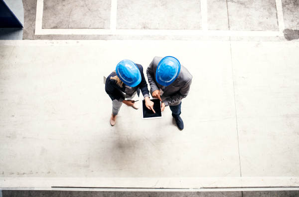 A top view of an industrial man and woman engineer with tablet in a factory, working. Copy space.