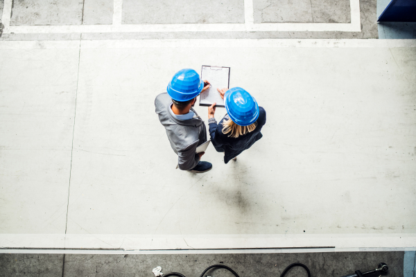 A top view of an industrial man and woman engineer with clipboard in a factory. Copy space.