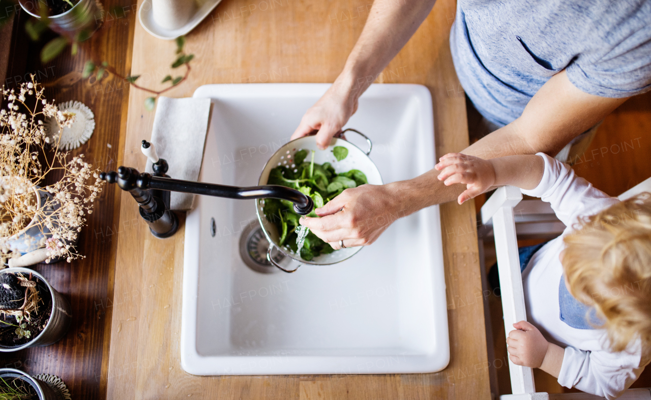 Unrecognizable young father with a toddler boy cooking. A man with his son making vegetable salad. Top view.