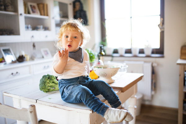 Toddler boy in the kitchen. A small boy sitting on a table.