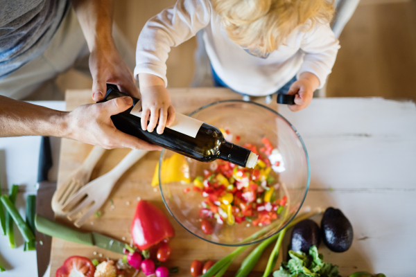 Unrecognizable young father with a toddler boy cooking. A man with his son making vegetable salad. Top view.