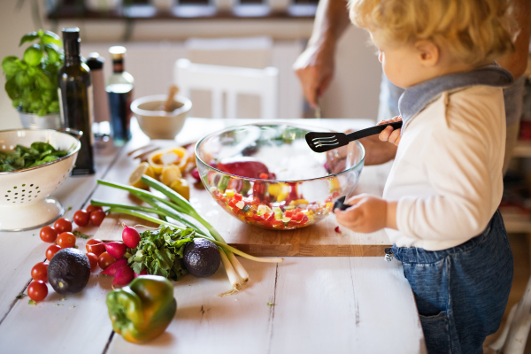 Young father with a toddler boy cooking. A man with his son making vegetable salad.