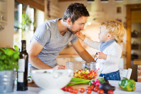 Young father with a toddler boy cooking. A man with his son making vegetable salad.