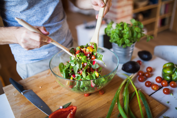 Unrecognizable man cooking. A man making vegetable salad.