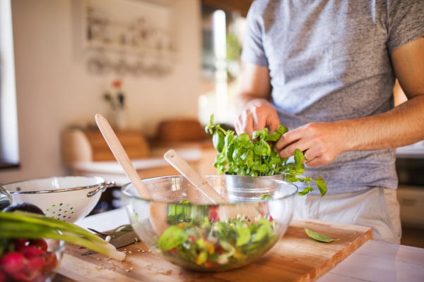 Unrecognizable young man cooking. A man making a vegetable salad