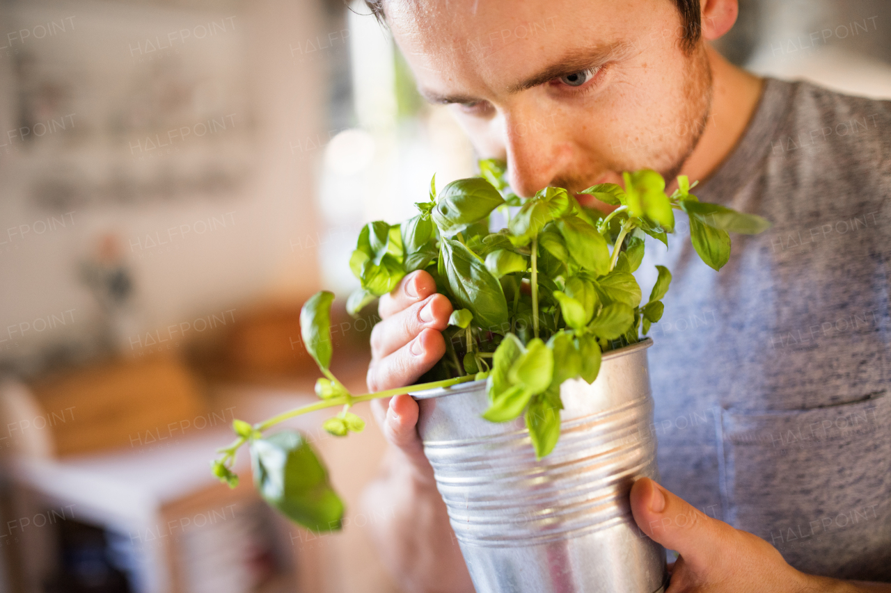 Young man cooking. A man holding a metal plant pot with herbs.