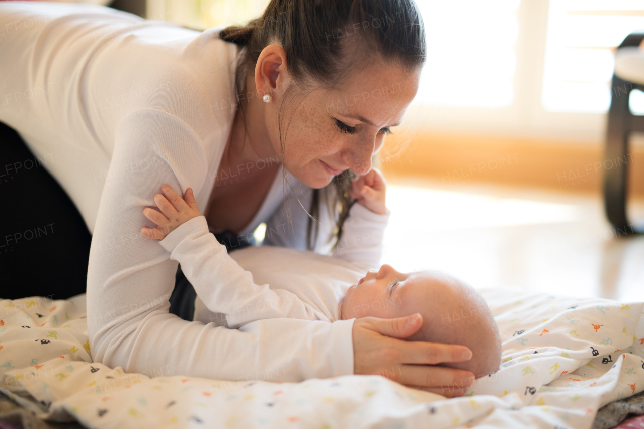 Beautiful mother holding head of her cute baby son lying on a blanket.