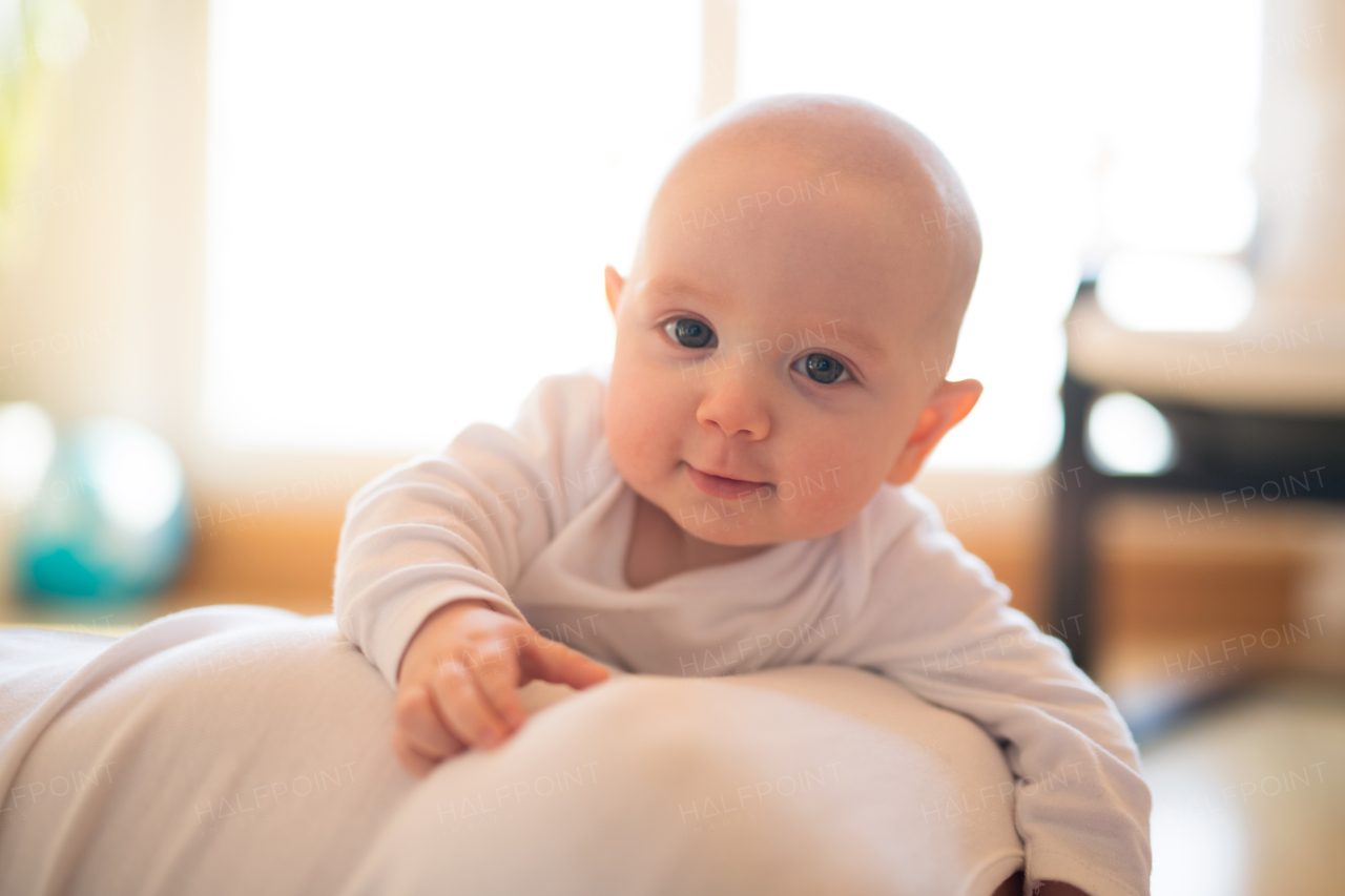 Close up of face of cute baby son lying on his unrecognizable mother smiling