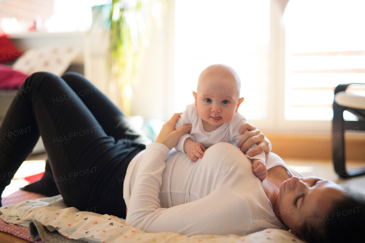 Beautiful mother lying on the floor, holding her cute baby son