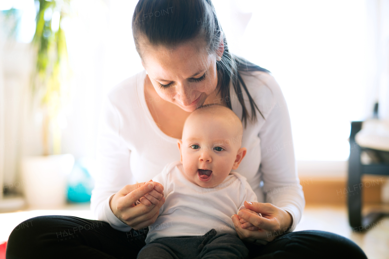 Beautiful mother in white t-shirt holding her cute baby son, sitting in her lap.