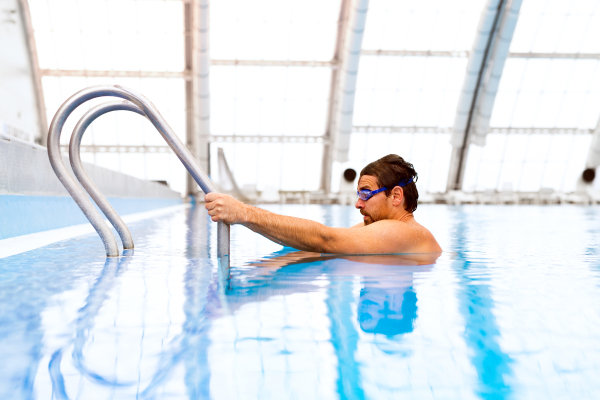 Man swimming in an indoor swimming pool. Professional swimmer practising in pool.