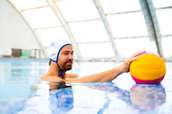 Water polo player in a swimming pool. Man doing sport.