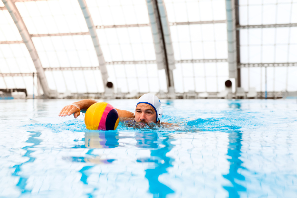 Water polo player in a swimming pool. Man doing sport.