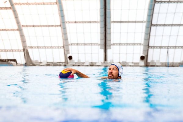 Water polo player in a swimming pool. Man doing sport.