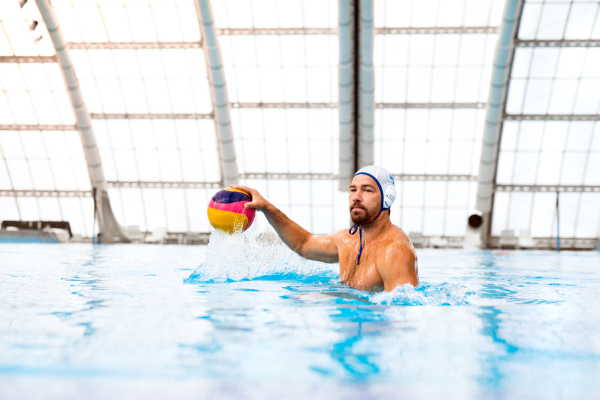 Water polo player in a swimming pool. Man doing sport.