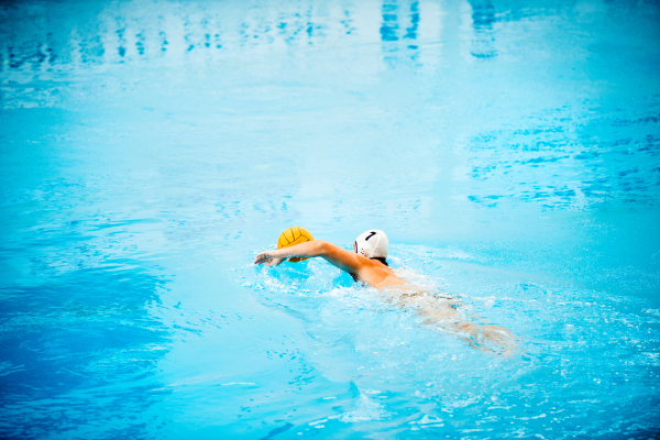 Water polo player in a swimming pool. Man doing sport.