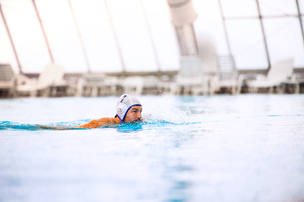 Water polo player in a swimming pool. Man doing sport.