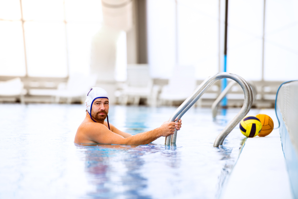 Water polo player in a swimming pool. Man doing sport.