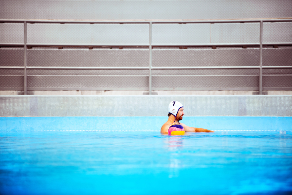 Water polo player in a swimming pool. Man doing sport.