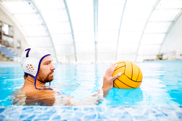 Water polo player in a swimming pool. Man doing sport.