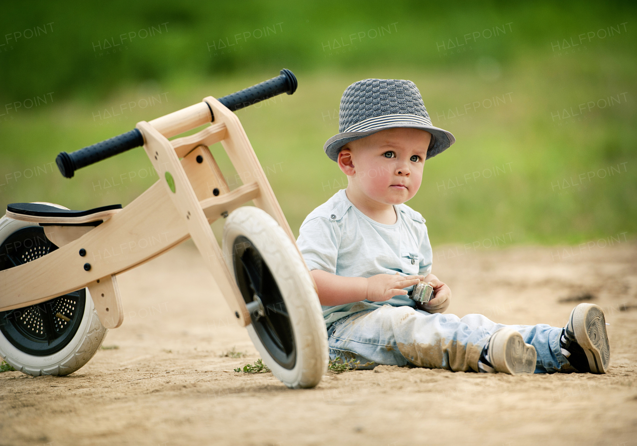 Cute toddler boy making first steps on the field road, summer time.