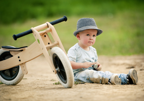 Cute toddler boy making first steps on the field road, summer time.