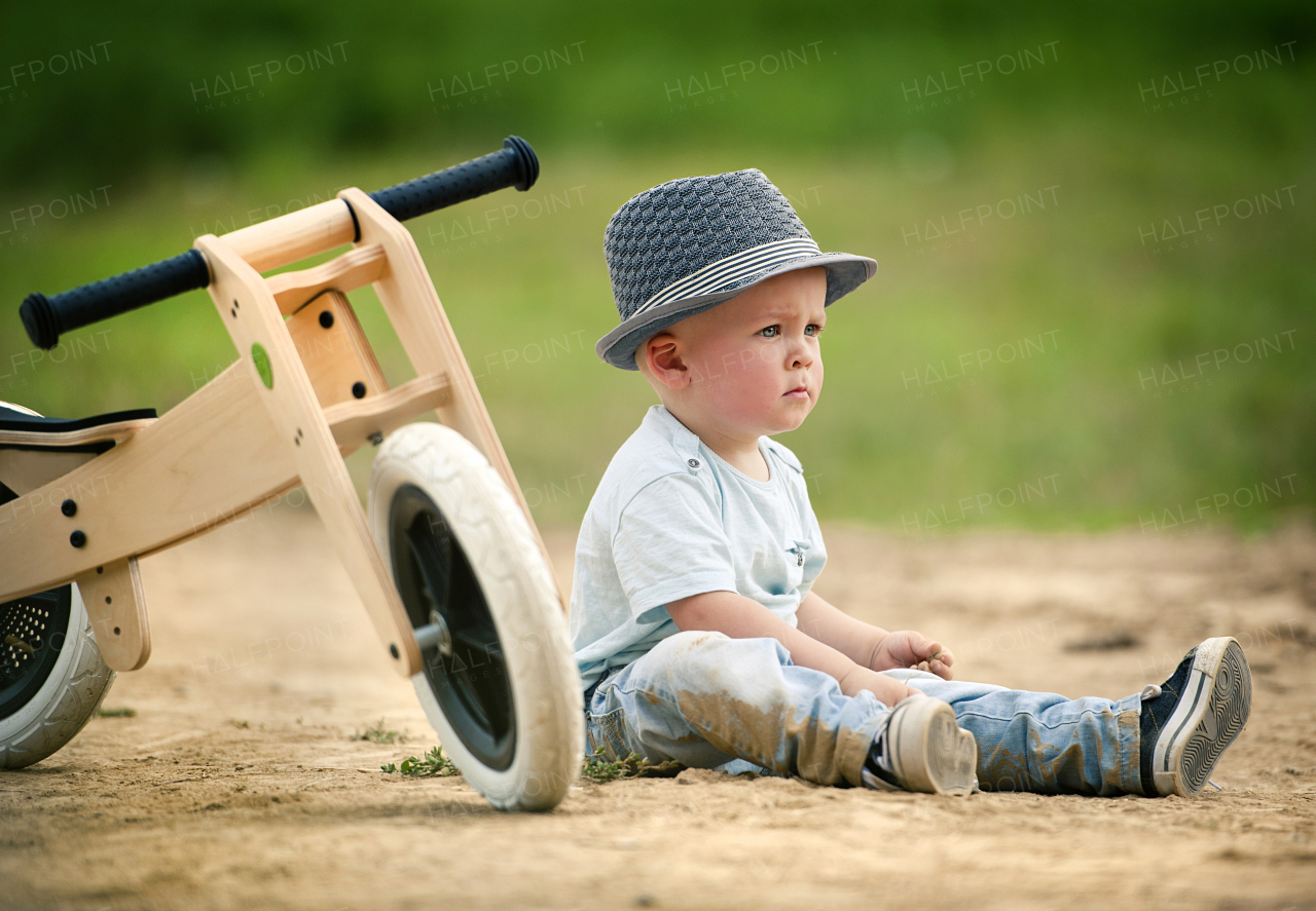 Cute toddler boy making first steps on the field road, summer time.