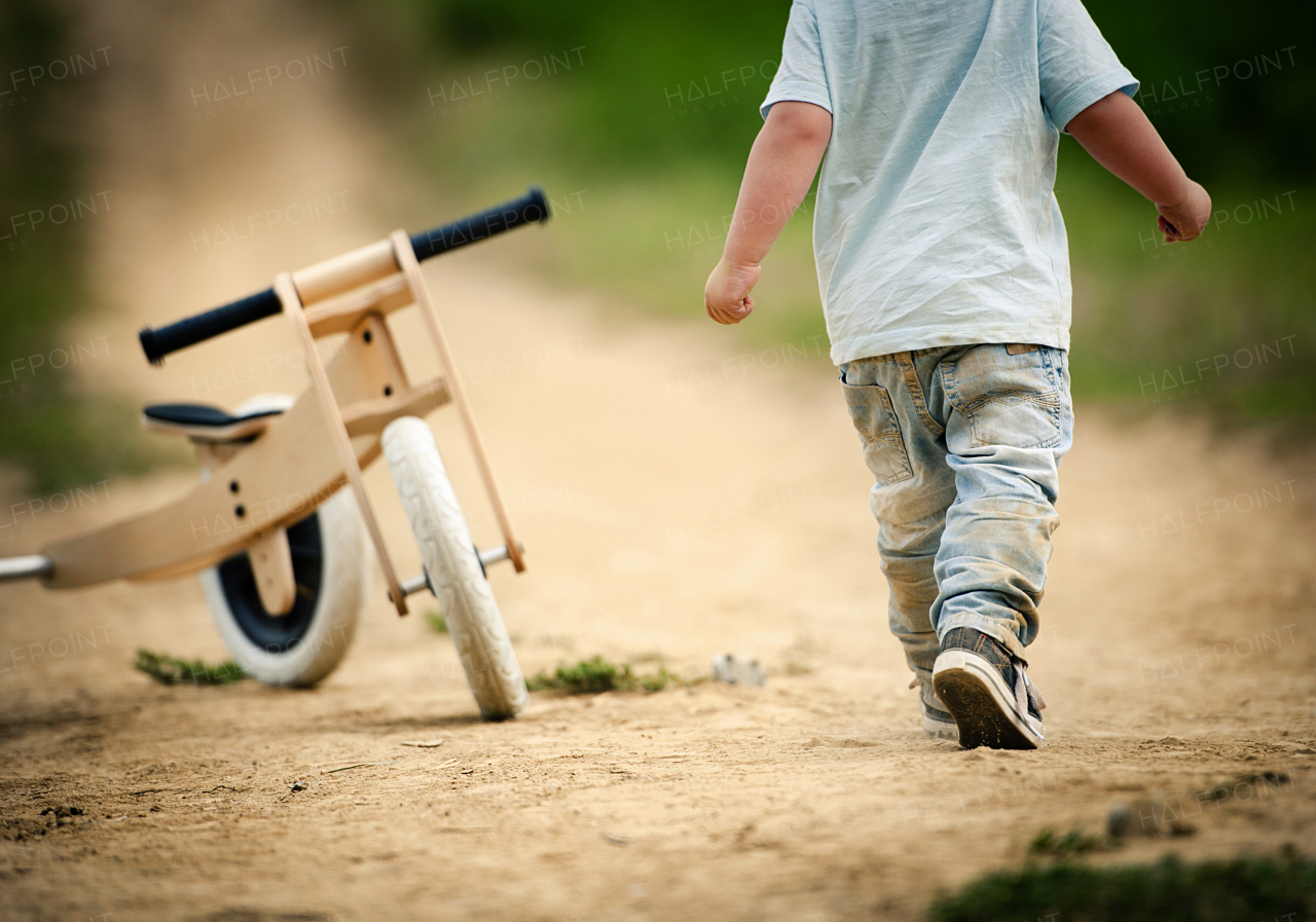 Cute toddler boy making first steps on the field road, summer time.