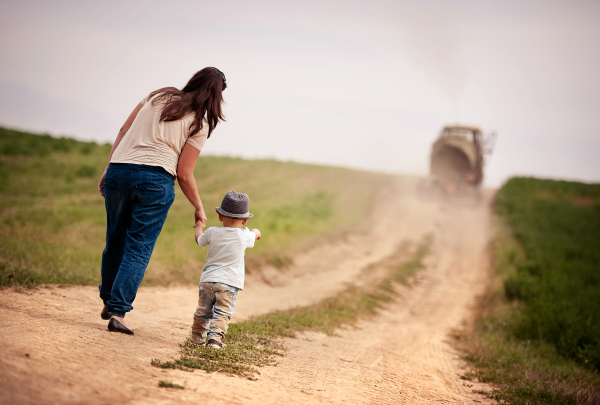 Young beautiful family walking on the road through fields, summer time.