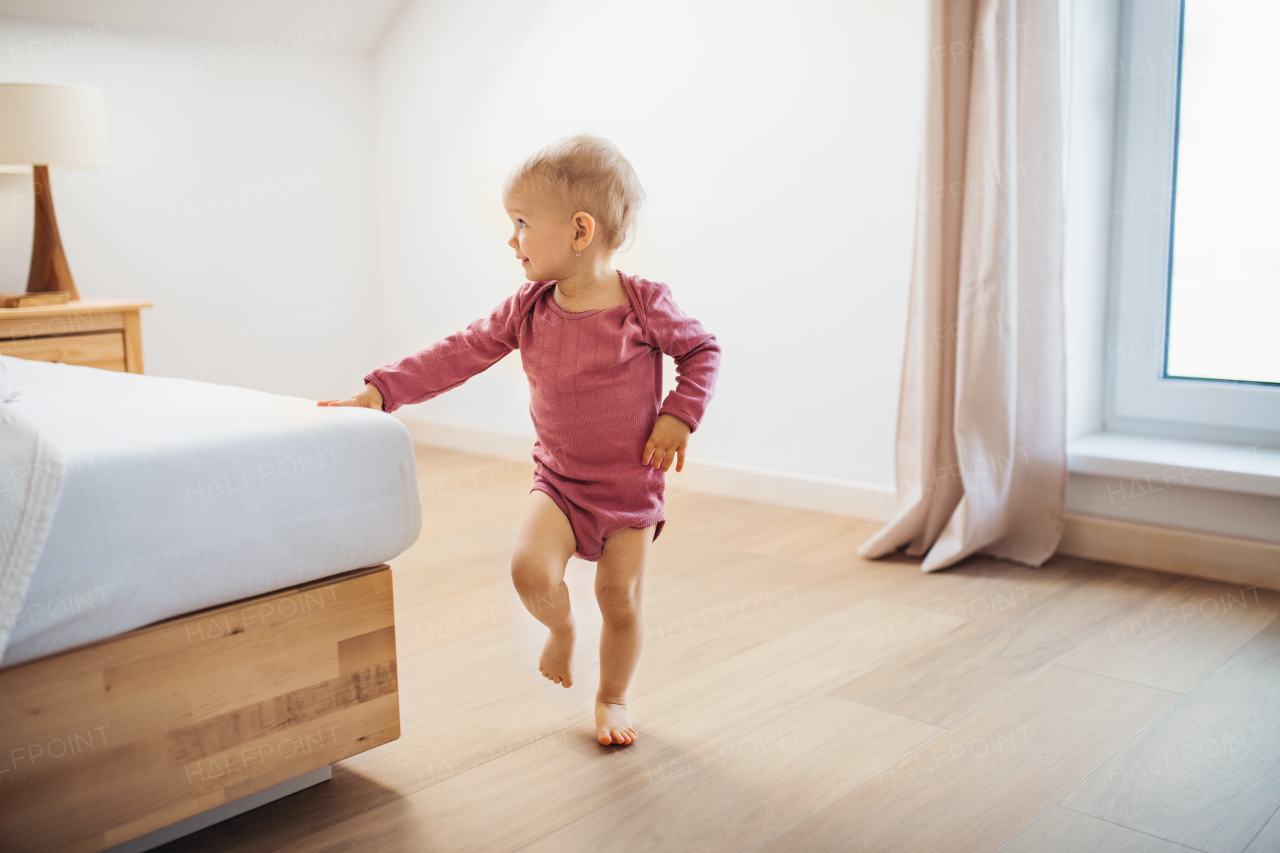 A small girl walking indoors in a bedroom. Copy space.