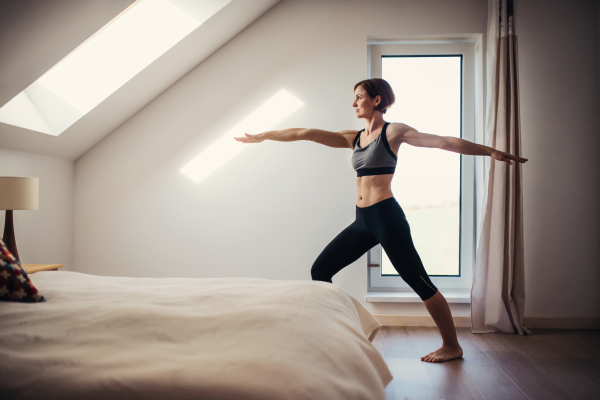 A side view of young woman doing exercise indoors in a bedroom. Copy space.