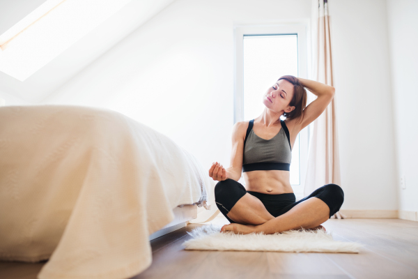 A happy young woman doing exercise indoors in a bedroom. Copy space.