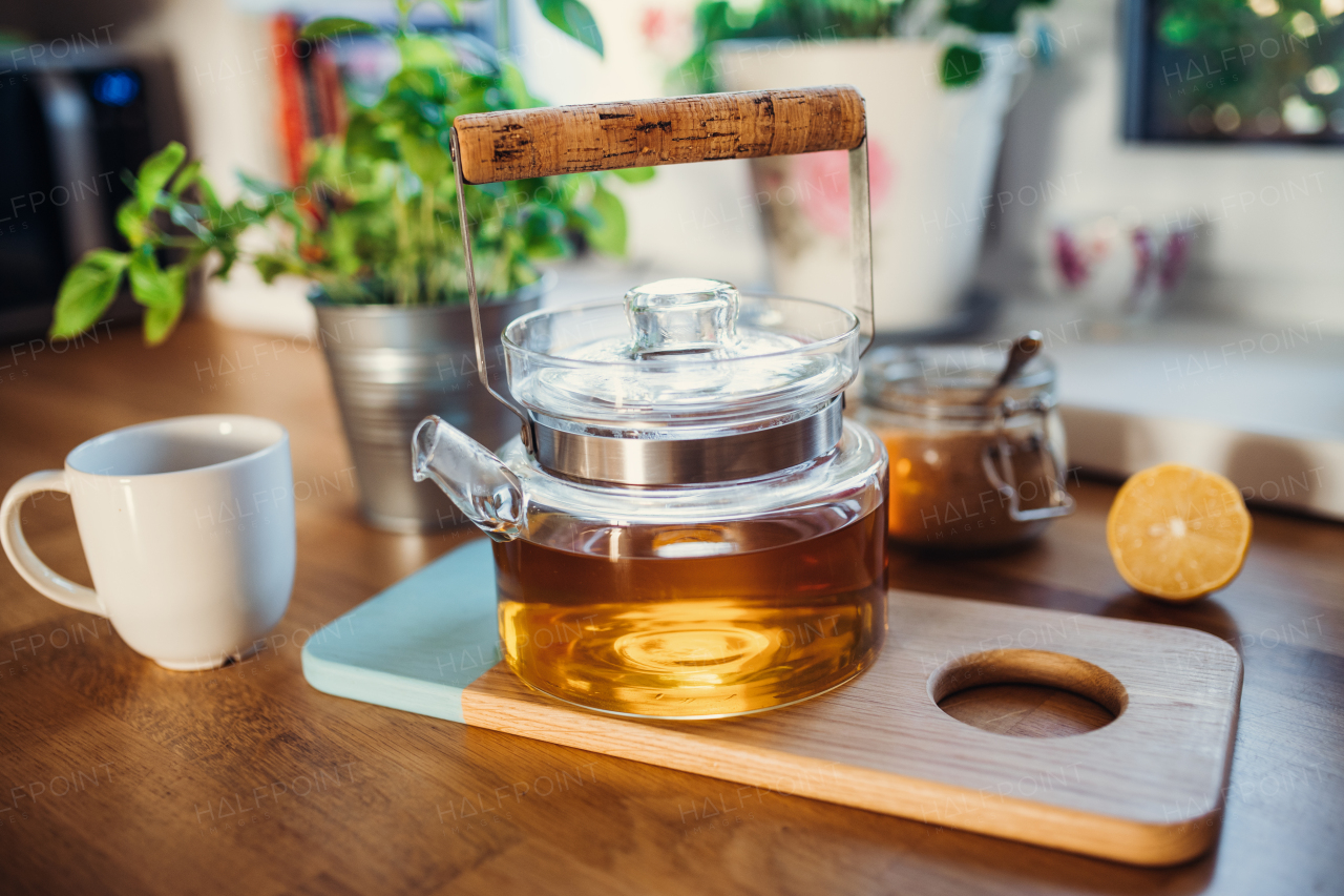 A composition of tea in a teapot, sugar, lemon and cup on wooden table.