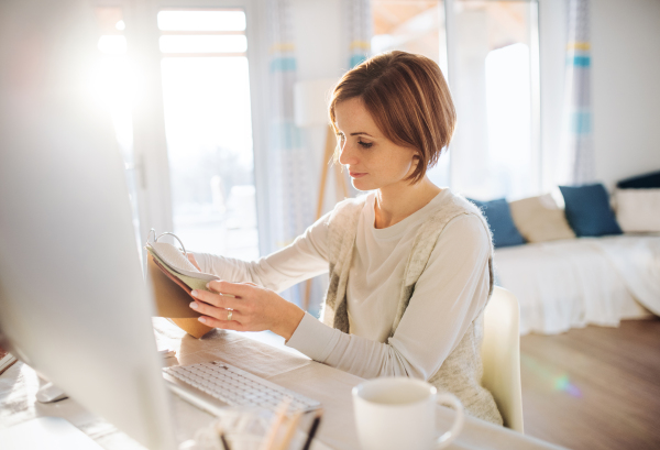 A happy young woman sitting indoors, working in a home office.