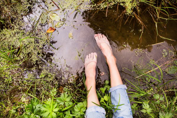 Feet of unrecognizable young woman sitting at the lake.