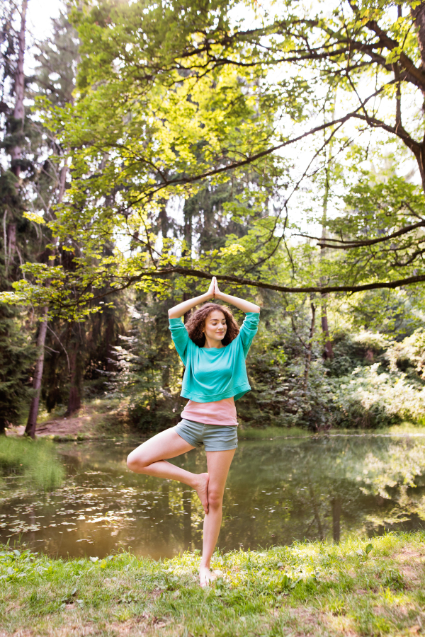 Beautiful girl practices yoga in the morning forest. Young woman sits,relaxes and meditates in nature.