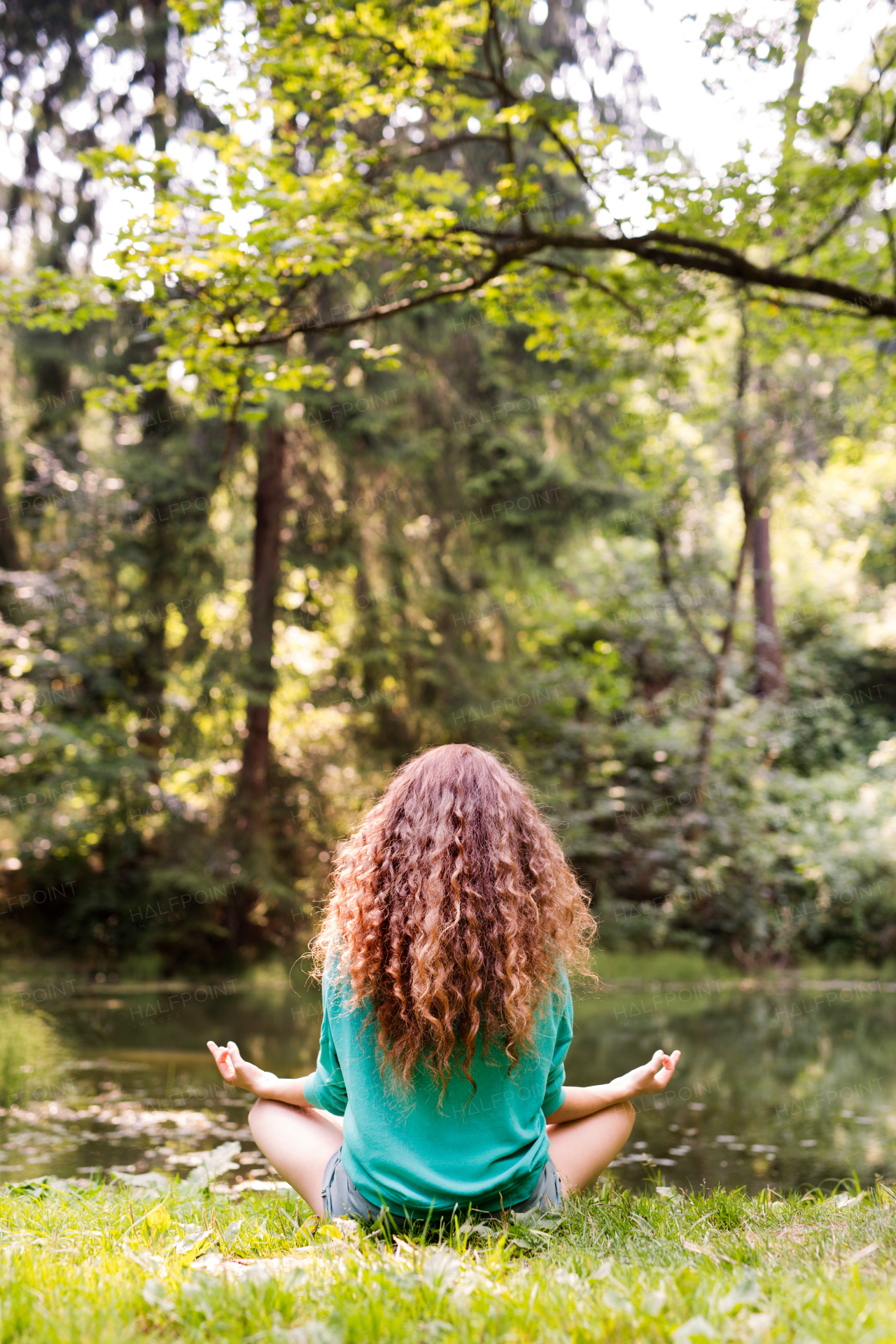 Unrecognizable girl practices yoga in the morning forest. Young woman sits,relaxes and meditates in nature.