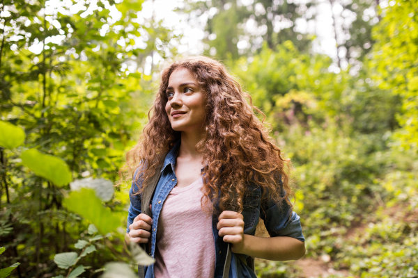 Teenage girl with backpack hiking in forest. Summer vacation adventure.