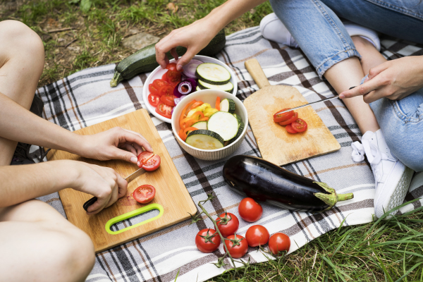 Group of unrecognizable teenagers camping and preparing food for barbecue.