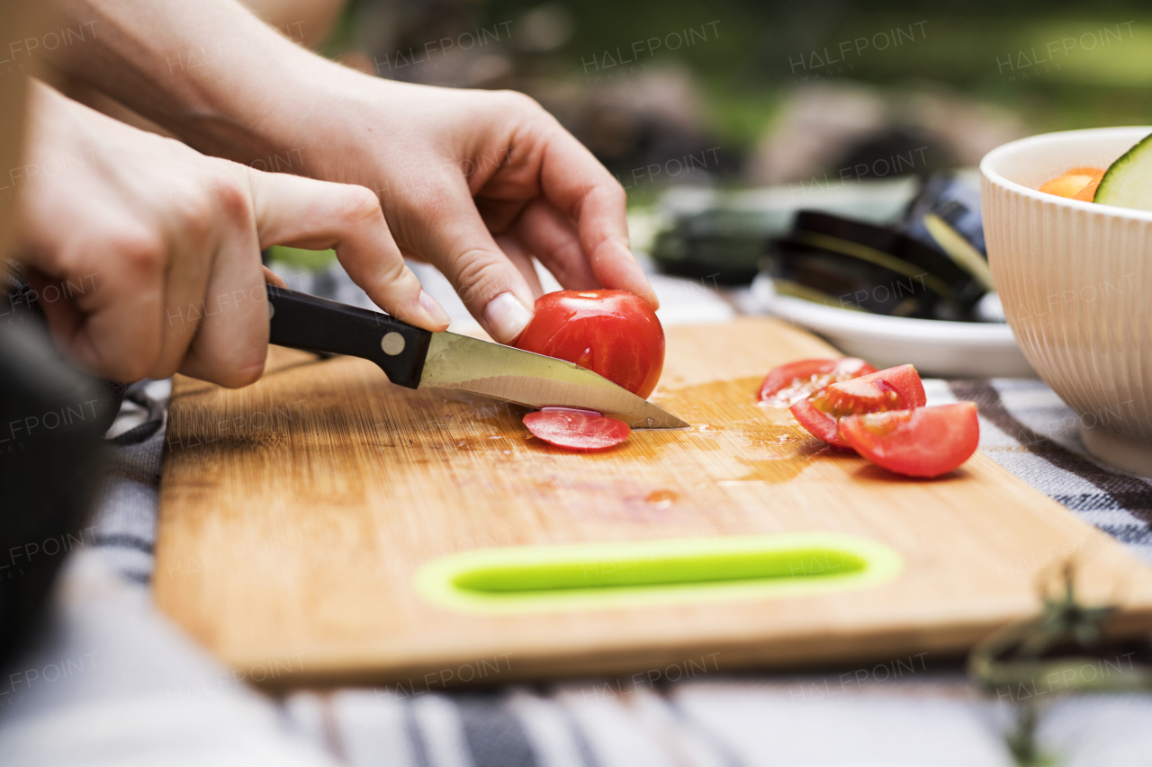 Unrecognizable teenagers camping and preparing food for barbecue. Close up.