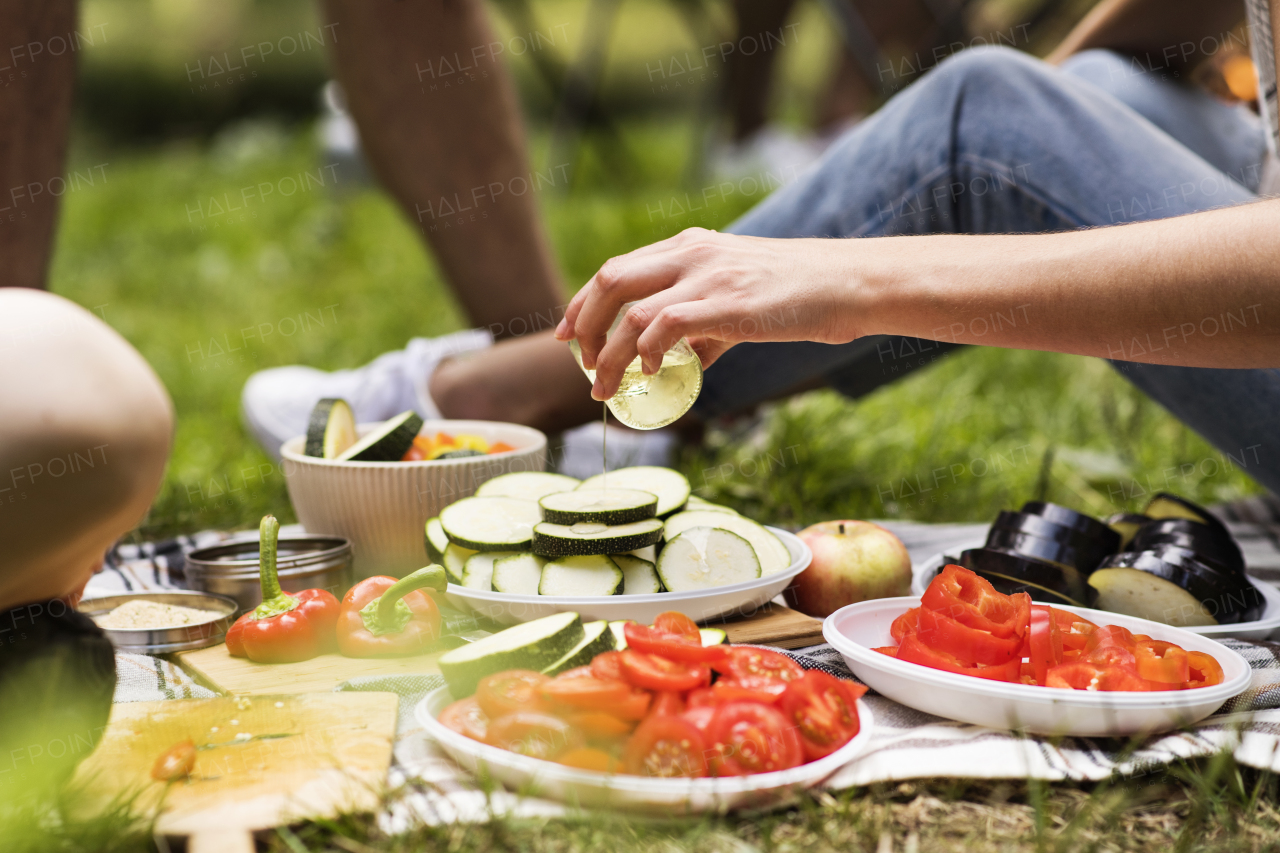 Unrecognizable teenagers camping and preparing food for barbecue.