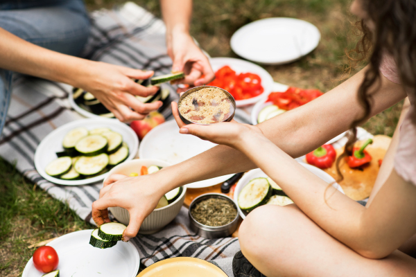 Group of unrecognizable teenagers camping and preparing food for barbecue.