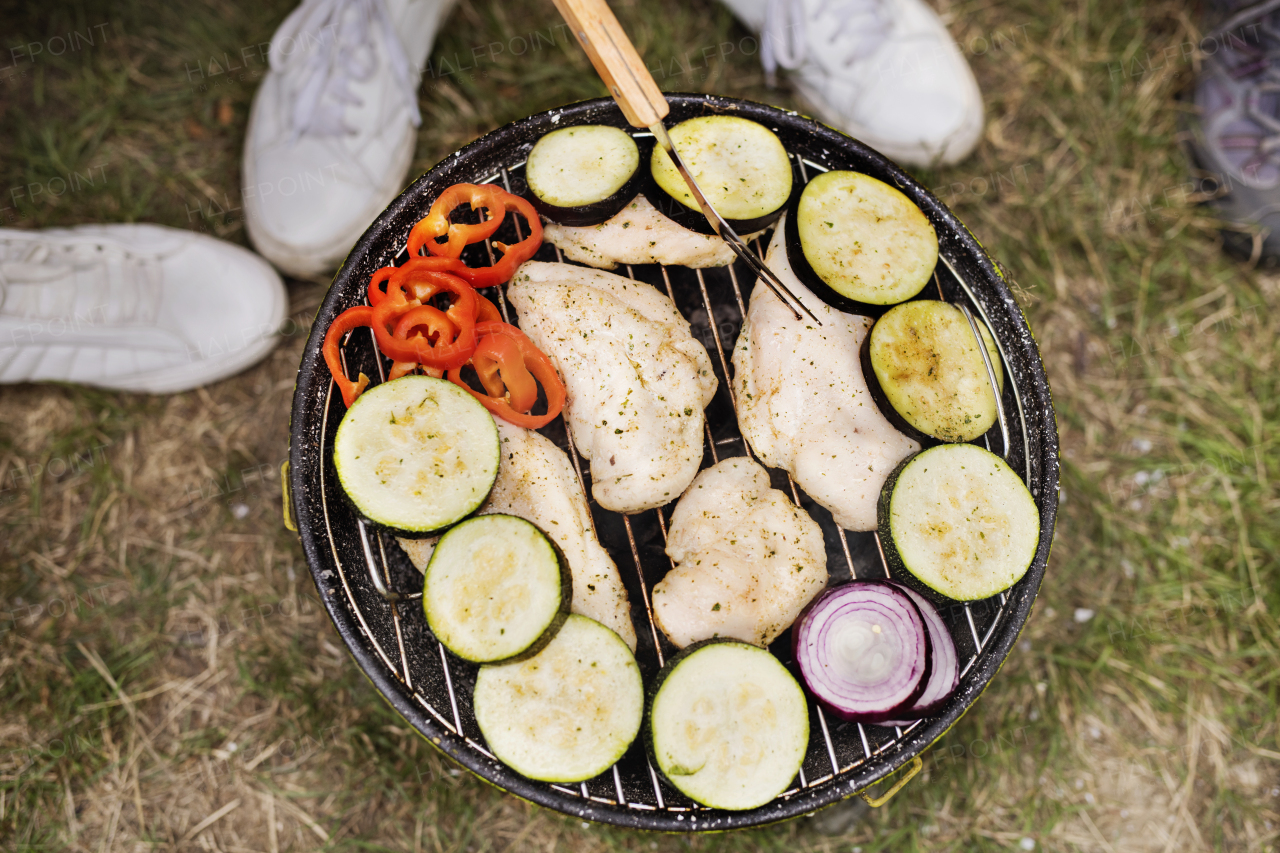 Group of unrecognizable teenagers cooking vegetables on barbecue grill. Close up.