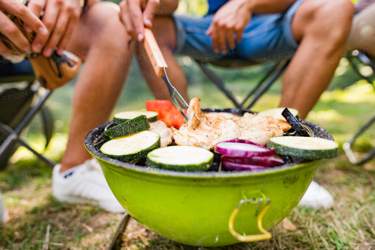 Group of unrecognizable teenagers cooking vegetables on barbecue grill.