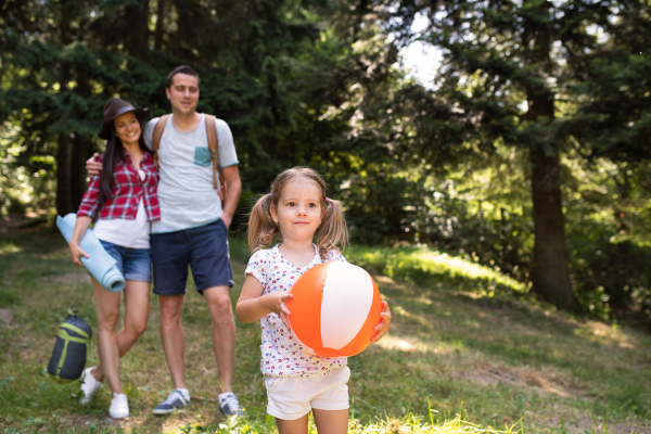 Beautiful parents with cute little daughter camping in forest.