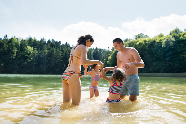 Young mother and father with their daughters in the the lake. Summer heat and water.