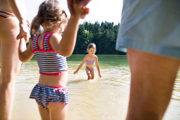 Little girls with their unrecognizable parents in the lake. Summer heat and water.