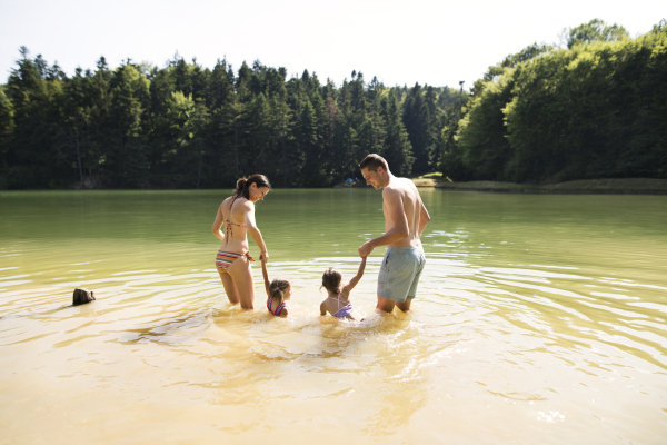 Young mother and father with their daughters in the the lake. Summer heat and water.