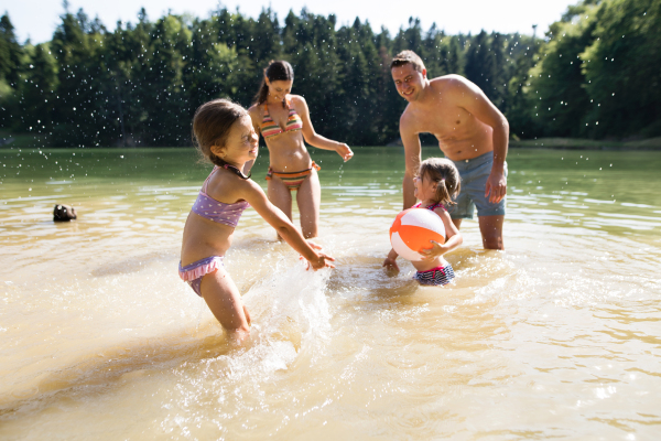 Young mother and father with their daughters in the the lake. Summer heat and water.